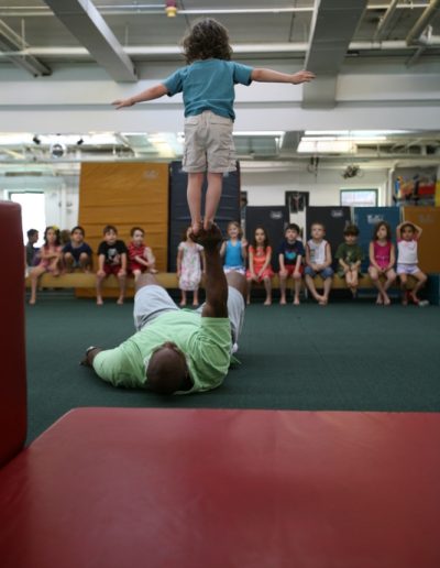A young boy performs a gymnastics routine in a gymnastics class.