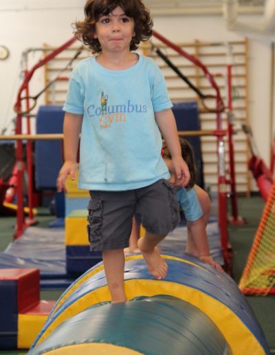 A young girl navigating an obstacle course at a toddler gym.