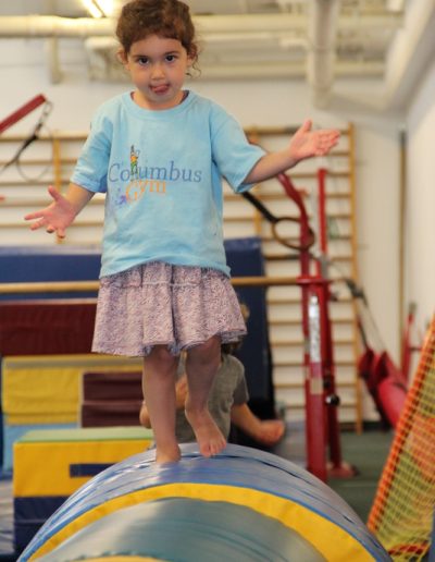 A young girl navigating an obstacle course at a toddler gym.