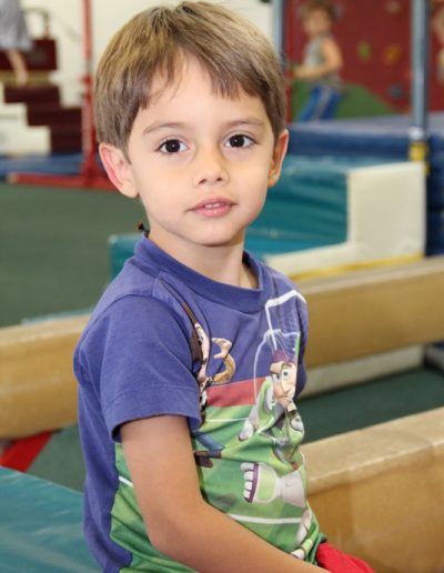 A young boy confidently balancing on a balance beam at Columbus Gym in New York.