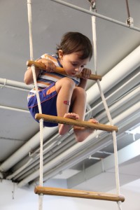 A young boy enjoying gymnastics for children at a kid party in an indoor gym.