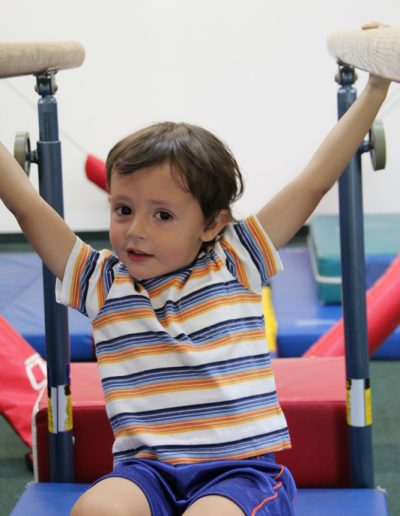 In Columbus Gym in New York, a young boy is passionately engaged in gymnastics, showcasing his skills and determination. The gym offers a specialized program of gymnastics for children, providing them with