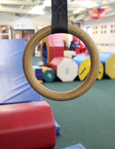 A wooden ring hanging in a gymnastics room, perfect for kid parties or gymnastics for kids.