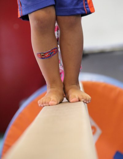 A child is gracefully balancing on a balance beam, showcasing their gymnastics skills.