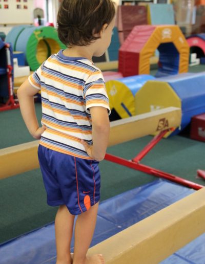 A young boy mastering his balance on the balance beam in a gym in Columbus.