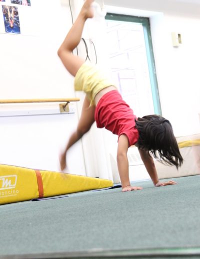 A young girl, demonstrating her impressive gymnastics skills, confidently performs a handstand on a balance beam at a Columbus Gym in New York.