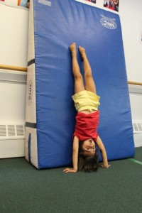 A young girl showcasing her gymnastics skills on a blue mat.