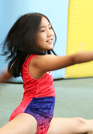 A young girl mastering gymnastic moves at an indoor gym in Columbus Gym in New York.