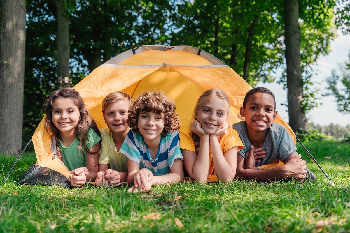 A group of kids posing in front of a tent.